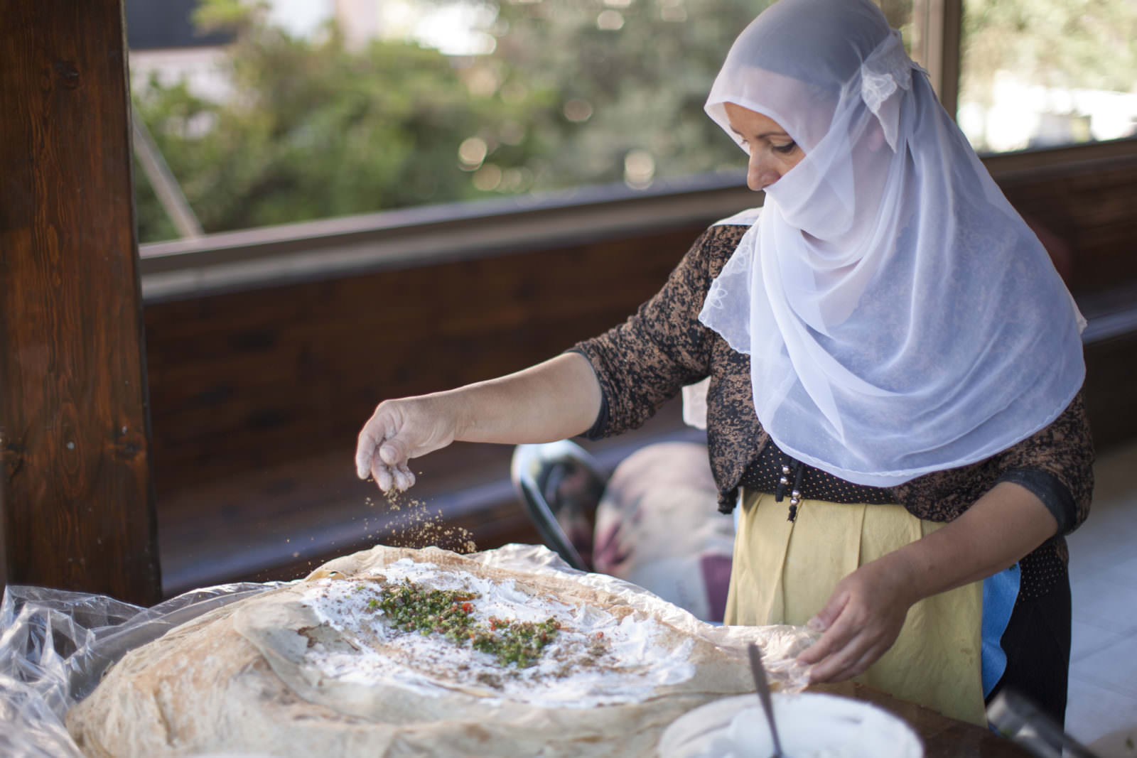 image preguntas viaje Israel Photo taken by Itamar Grinberg for the Israeli Ministry of Tourism. A Druze woman preparing a traditional traditional wraps with pitta as the base.