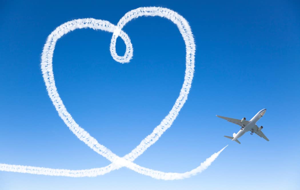 Airplane flying with the heart shape in the sky