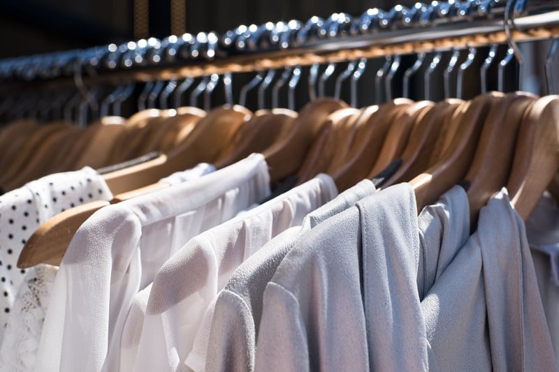 43436952 - white and gray tone clothes hanging on a rack in a designer clothes store, selective focus, horizontal