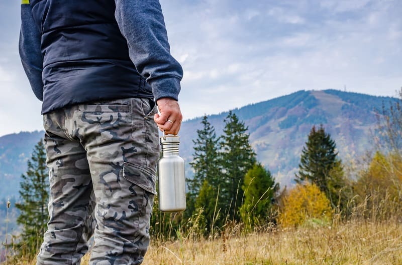 Man holding a bottle on the carpathian mountains background