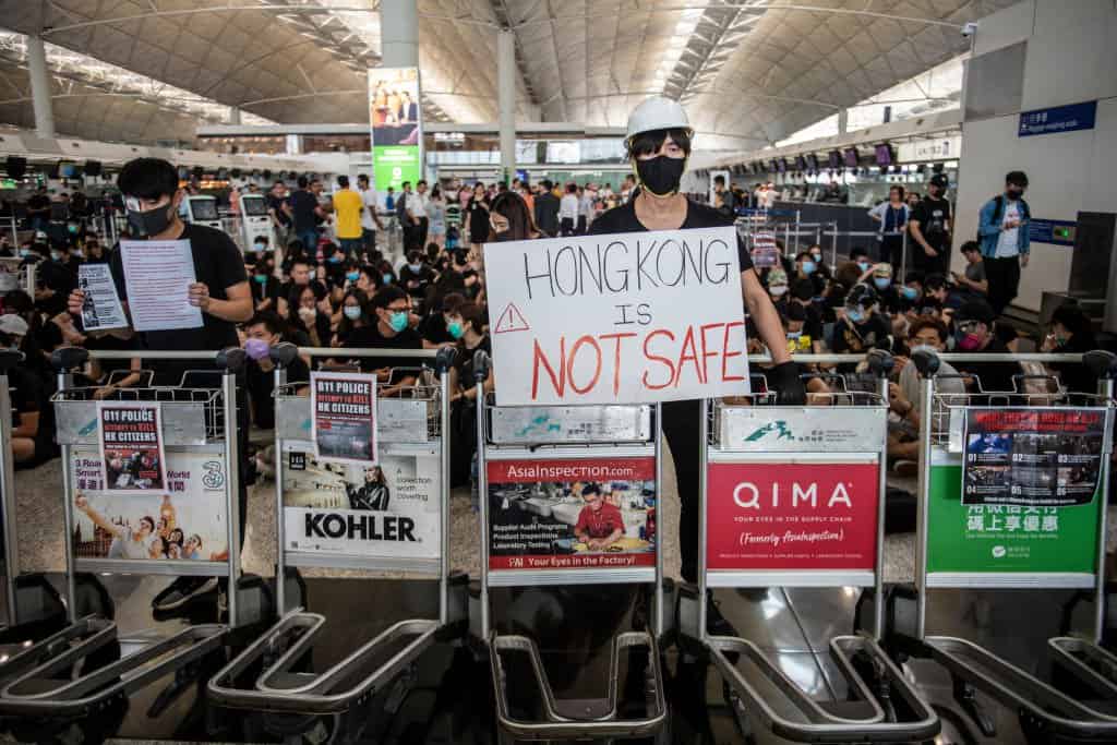 A Protester standing behind luggage trolleys while holding up a placard  in Hong Kong International Airport in Hong Kong on August 12, 2019 , Tens of Thousands Protester are seen gather in Hong Kong international airport in protest of Police Brutally and the extradition bill -- Protester Clash with Police yesterday in Hong Kong.  (Photo by Vernon Yuen/NurPhoto via Getty Images)