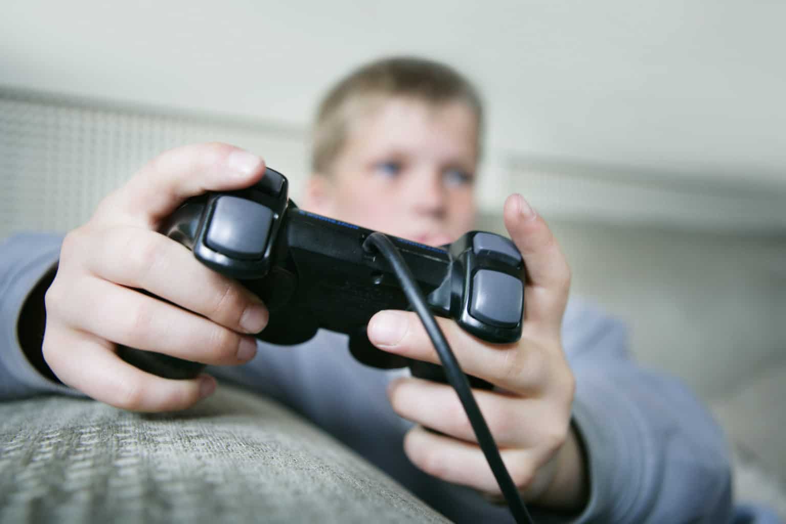 Boy (9-11) playing games console (focus on hands and control)