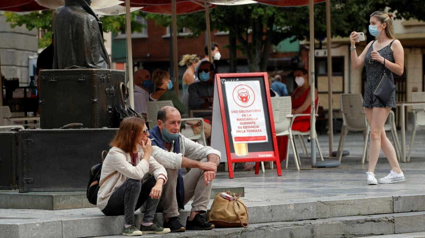 OVIEDO, 13/08/2020.- Una pareja de turistas fuman sentados en una plaza del centro de Oviedo, este jueves. El Gobierno asturiano está valorando "con prudencia" la posibilidad de prohibir fumar en la vía pública en función de cómo evolucione la pandemia de la covid-19 y desde la perspectiva jurídica para definir "hasta qué punto" se podría tomar esa decisión desde el ámbito competencial del Principado. EFE/Alberto Morante