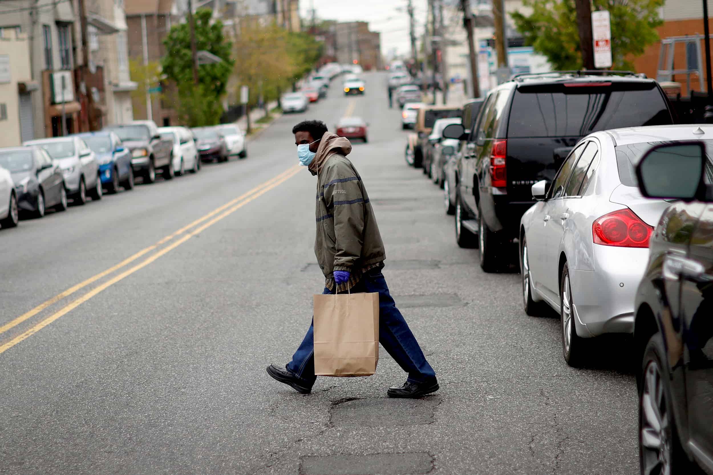 A man carries a bag containing meals, face masks and other personal protective supplies during a distribution to residents in need outside the NAN Newark Tech World during the outbreak of the coronavirus disease (COVID-19) in Newark, New Jersey, U.S., May 6, 2020. REUTERS/Mike Segar - RC25JG9FG201