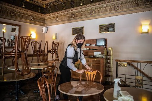 epa08441693 A waiter wearing a protective face mask arranges the furniture ahead of the reopening of the Cafe Savoy in Prague, Czech Republic, 24 May 2020. Starting on 25 May, restaurants and cafes across the country will be allowed to again serve seated customers indoors as the next phase of the lifting of coronavirus-induced restrictions kicks off. The Czech government is gradually easing the lockdown measures it had imposed back in March in a bid to slow down the spread of the pandemic COVID-19 disease caused by the SARS-CoV-2 coronavirus.  EPA/MARTIN DIVISEK