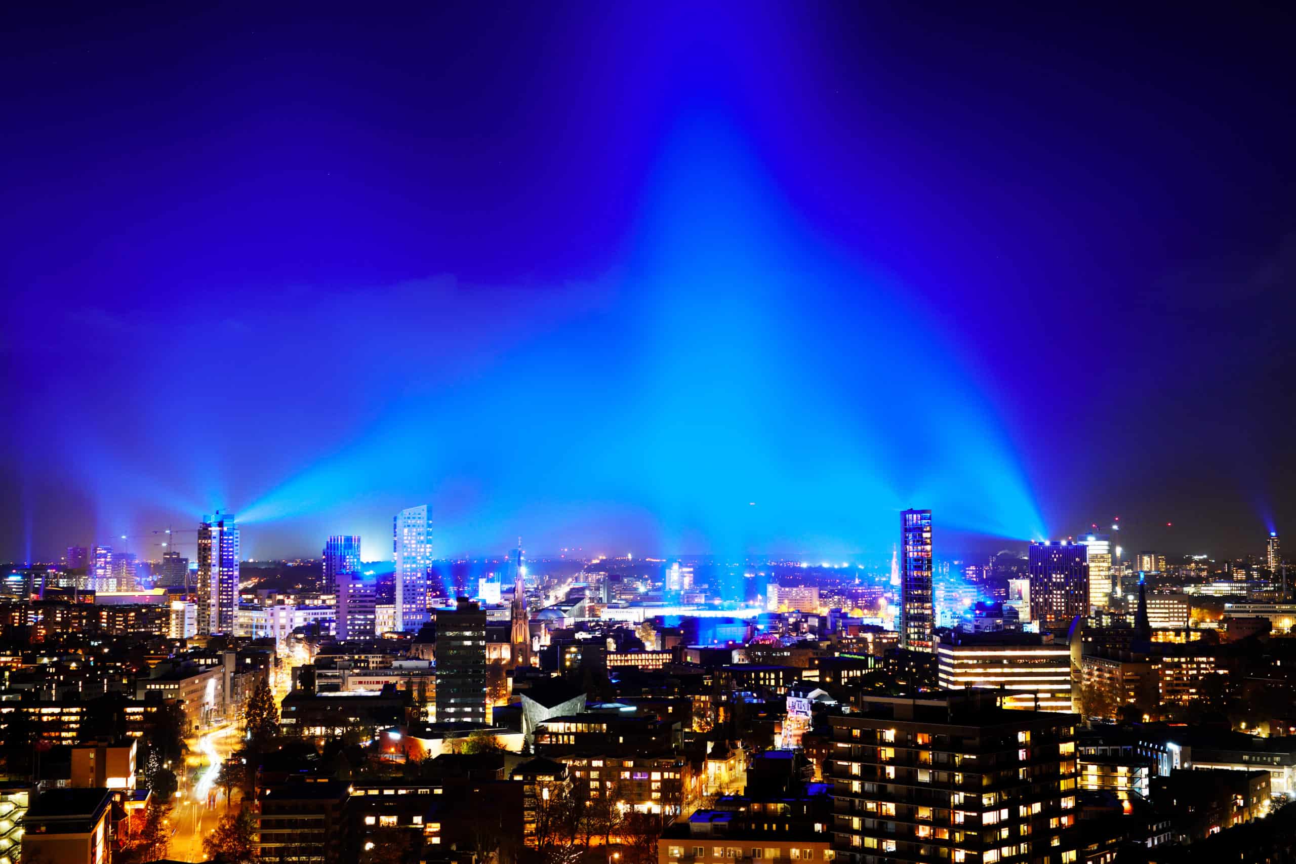 Nederland, Eindhoven, 12 november 2020. 
Met Connecting the Dots creëert het Eindhovense lichtfestival GLOW het grootste lichtkunstwerk ooit over 80 km2. 
De Finse lichtkunstenaar Kari Kola zorgt met 1500 lampen voor een blauwe mantel van licht over de stad. 1000 rode verlichte ballonnen door de Nederlandse kunstenaar Ivo Schoofs brengen verbinding aan. Eindhovens kunstenaar Hugo Vrijdag riep kinderen op een persoonlijke GLOWdot te maken, volwassenen deden ook mee. Er kunnen misschien wel 20.000 van deze klein lichtkunstwerkjes achter de ramen hangen. 
Vanwege de corona-pandemie is er dit jaar geen gebruikelijke GLOW looproute. Het lichtspektakel is overal in de stad en tot ver daarbuiten te zien. 
foto: GLOW / Bart van Overbeeke