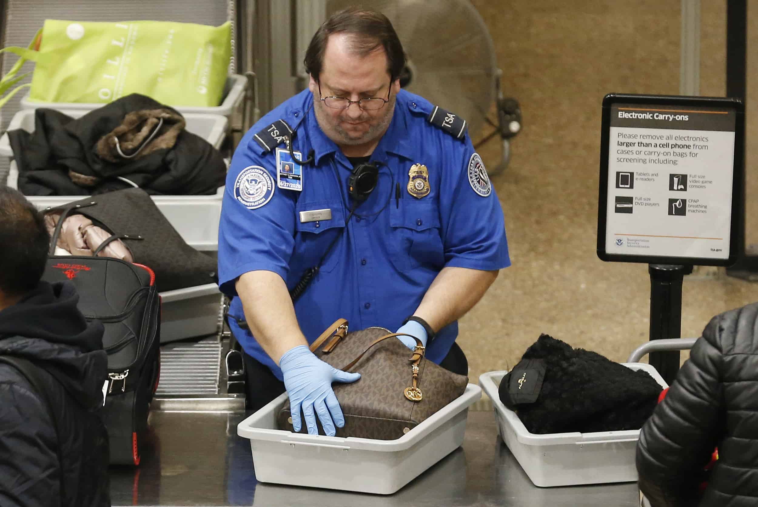 A TSA worker helps passengers at the Salt Lake City International Airport, Wednesday, Jan. 16, 2019, in Salt Lake City. The government shutdown has generated an outpouring of generosity to TSA agents and other federal employees who are working without pay. In Salt Lake City, airport officials treated workers from the TSA, FAA and Customs and Border Protection to a free barbecue lunch as a gesture to keep their spirits up during a difficult time. (AP Photo/Rick Bowmer)