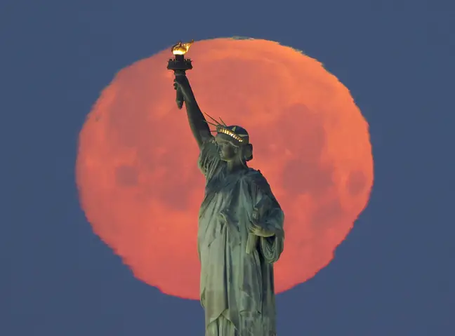 [IMÁGENES] Así se vio la superluna rosa en diferentes partes del mundo y en Nueva York, creando una aureola alrededor de la Estatua de la Libertad