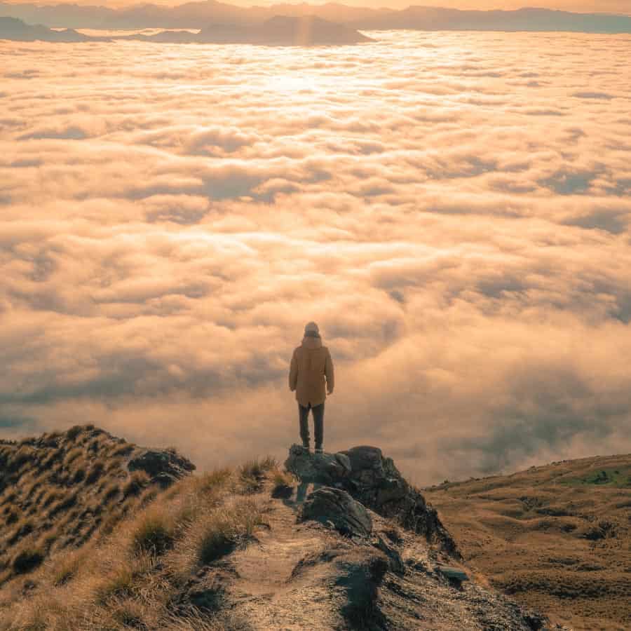 persona en la cima de una montaña por encima de las nubes