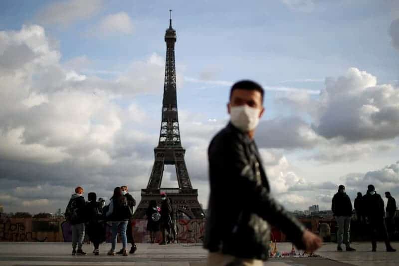 pasaporte sanitario Francia: no será obligatorio usar mascarilla en los lugares que pidan pasaporte sanitario Personas caminando con mascarilla frente a la Torre Eiffel