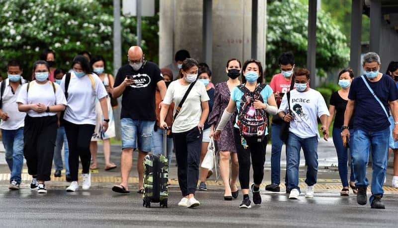 Personas cruzando la calle en Singapur, usando mascarilla