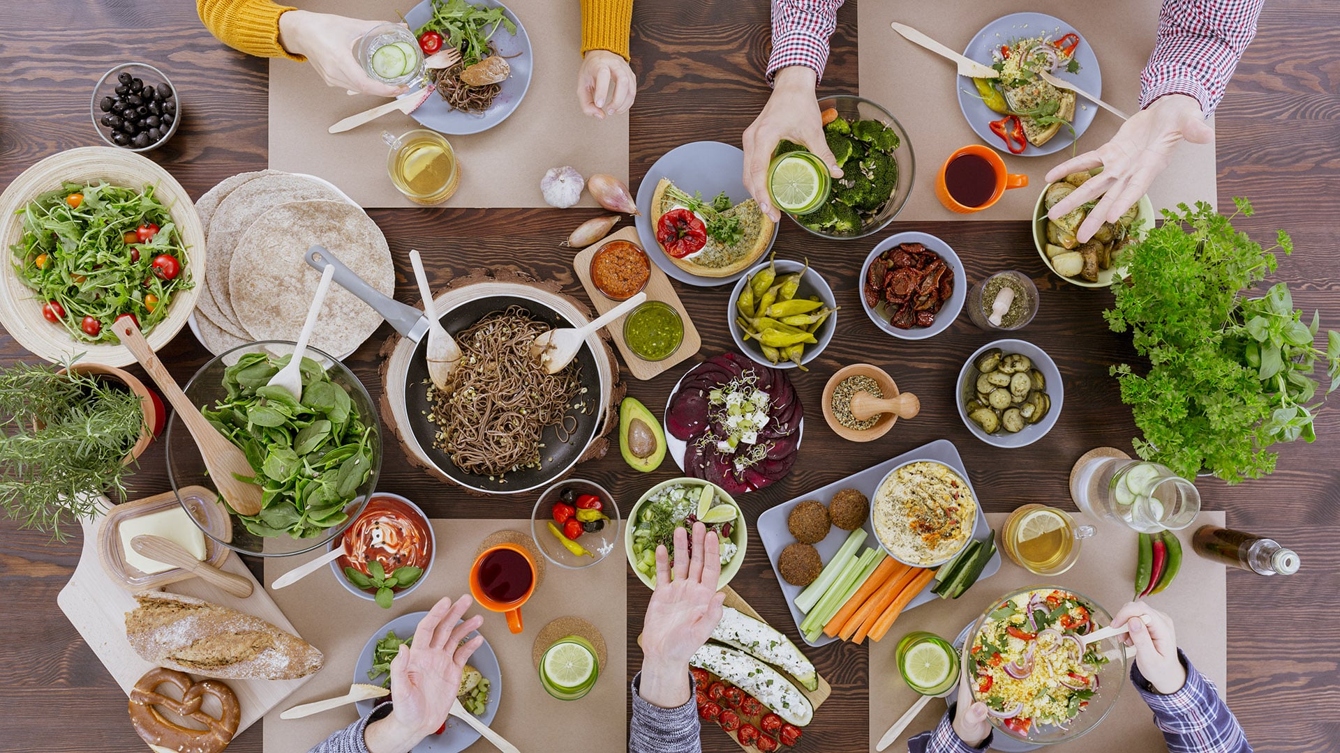 People eating healthy food, drinking water, sitting beside wood table