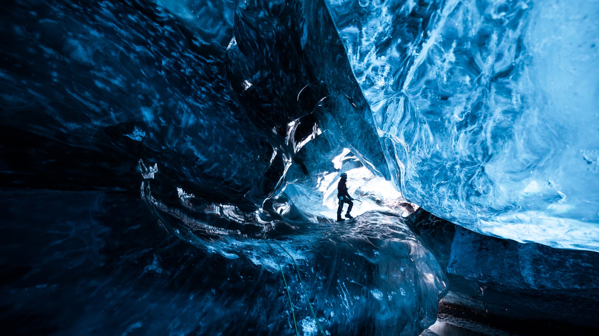 Inside an icecave in Vatnajokull, Iceland. A climber silhoutted against the ice. The ice is thousands of years old and so packed it is harder than steel and crystal clear. These caves are formed by meltwater that rushes from over and underneath the glacier and creates these wonderful sights