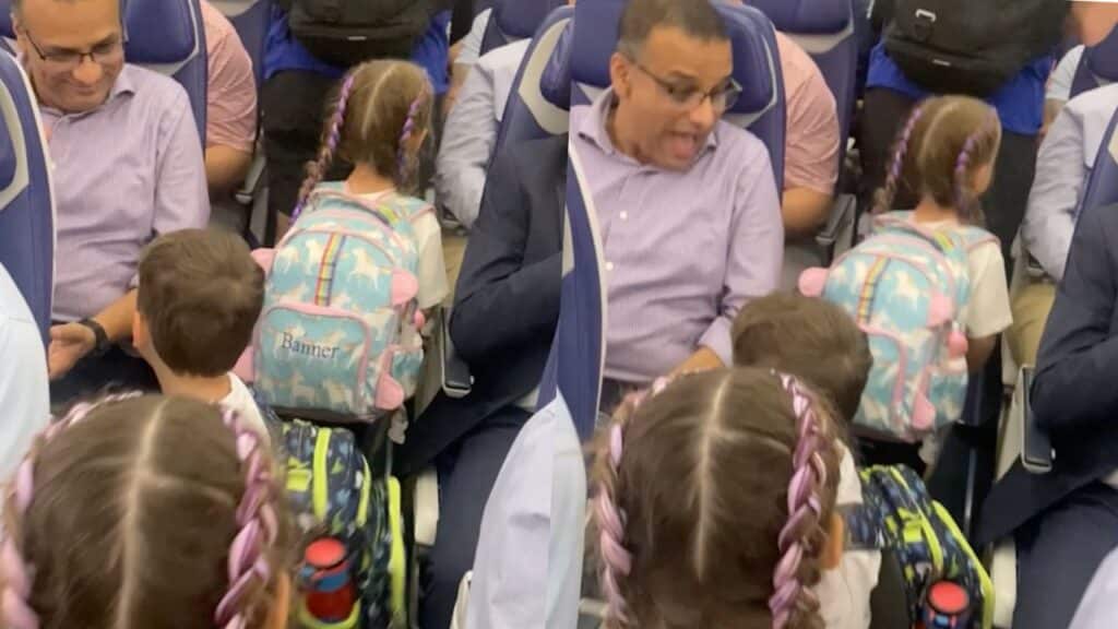 Niño muestra orgulloso su nueva mochila de dinosaurio a todos los pasajeros del avión