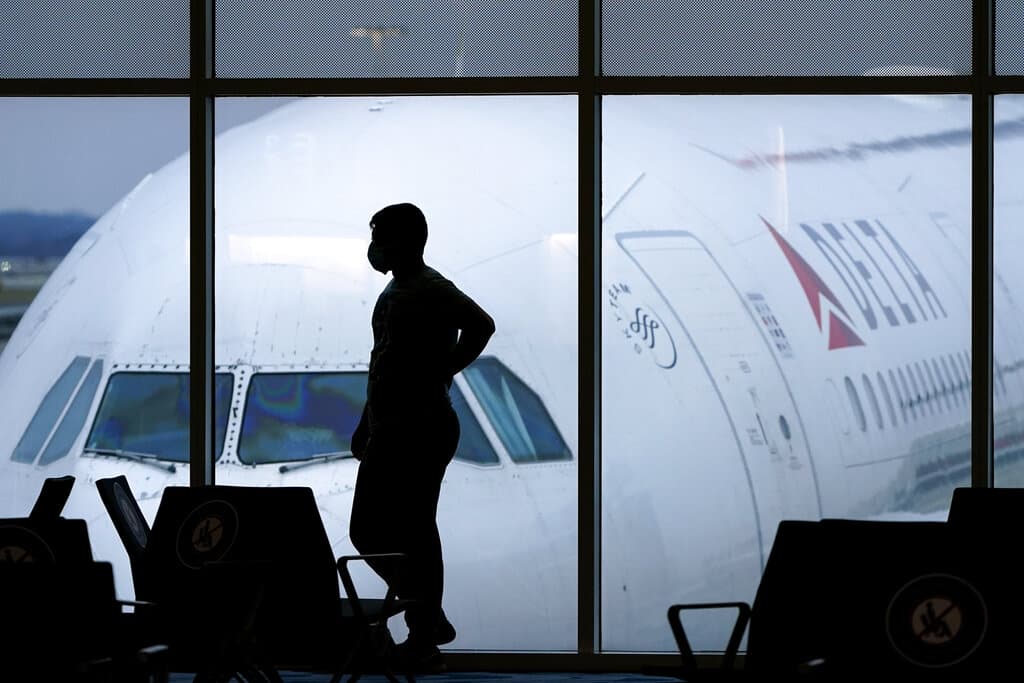 FILE - In this Feb. 18, 2021, photo, a passenger wears a face mask to help prevent the spread of the new coronavirus as he waits for a Delta Airlines flight at Hartsfield-Jackson International Airport in Atlanta. More than 1,000 airline flights were canceled as of Saturday afternoon,  May 28, 2022, according to flight tracking website FlightAware. Hartsfield-Jackson International Airport in Atlanta, where Delta is based,  and has its largest hub, is heavily affected by the travel snags. (AP Photo/Charlie Riedel, File)