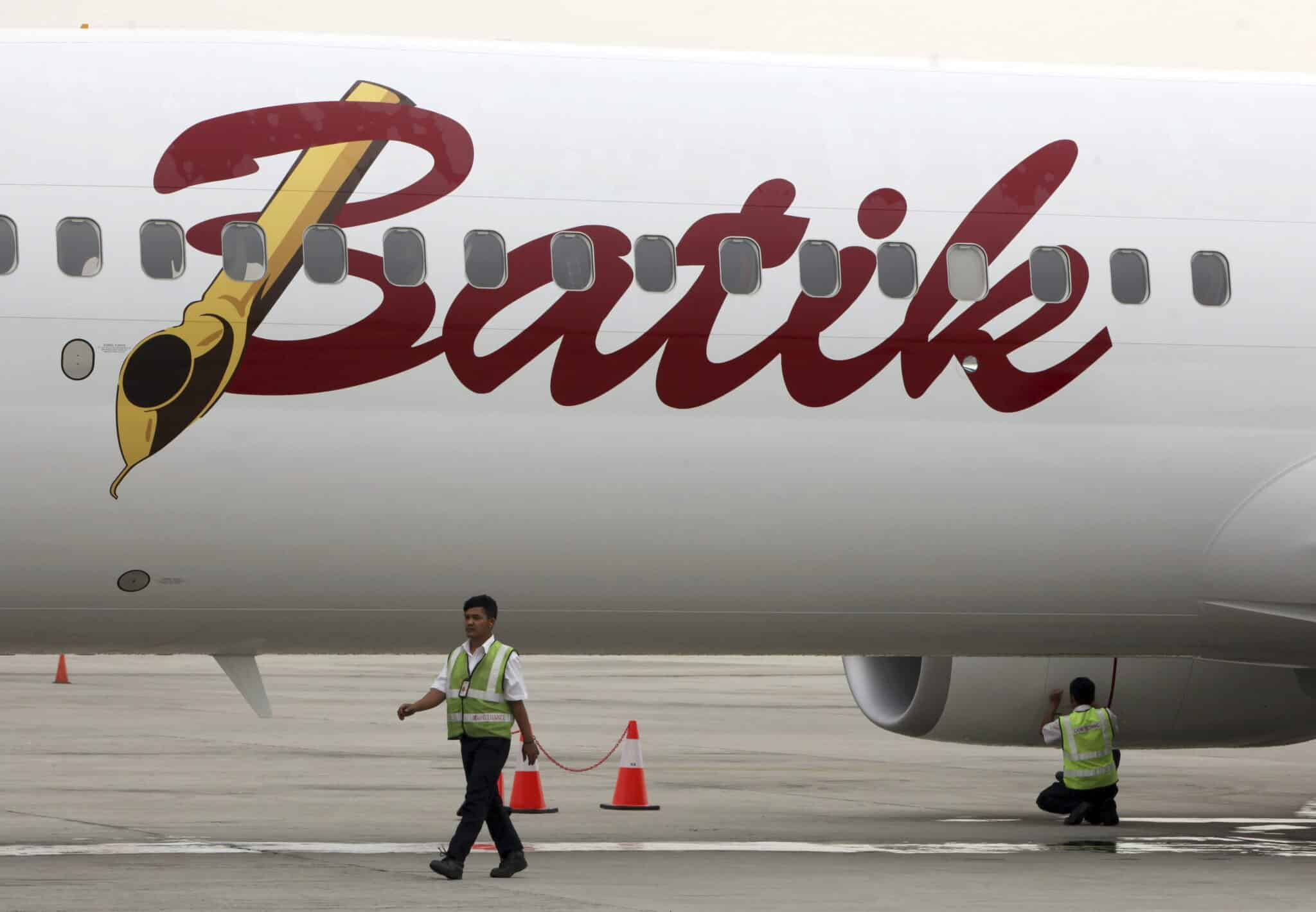 Trabajadores aeroportuarios caminan junto a un avión de Batik Air. EFE/ Adi Weda