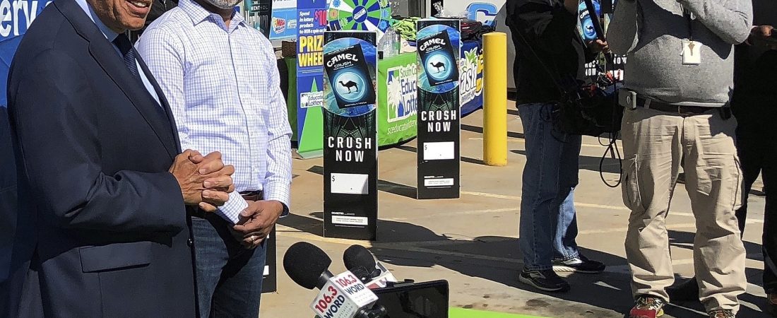 FILE-In this Wednesday, Oct. 24, 2018 file photo, South Carolina Education Lottery Chief Operating Officer Tony Cooper, left, and KC Mart owner CJ Patel, right, speaks to reporters about the winning ticket sold at the Simpsonville, S.C., store. Nearly everyone in this small town has a theory for the city's billion-dollar mystery: Who won the $1.5 billion Mega Millions jackpot announced last October? (AP Photo/Jeffrey Collins, File)