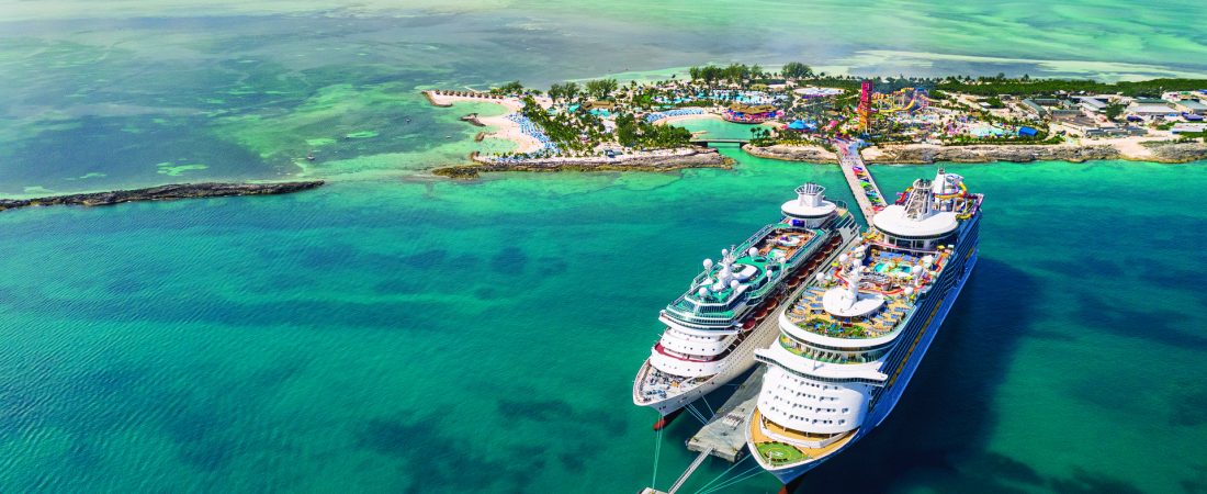 Perfect Day at CocoCay, Labadee, private island, aerial, wide drone shot of island, Navigator of the Seas and Majesty of the Seas docked at pier, overhead front view of ships, ocean horizon, Up, Up, and Away balloon in distance