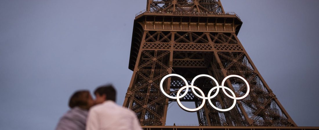 PARIS, FRANCE - JUNE 27: A couple kiss under the Eiffel Tower as the Olympic Rings are displayed during previews ahead of the Paris 2024 Olympic Games on June 27, 2024 in Paris, France. (Photo by Ryan Pierse/Getty Images)