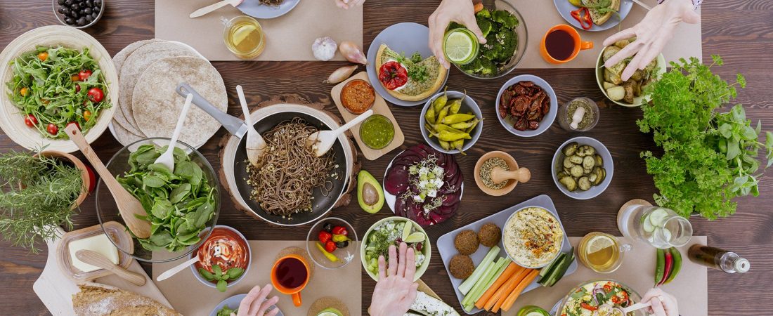 People eating healthy food, drinking water, sitting beside wood table