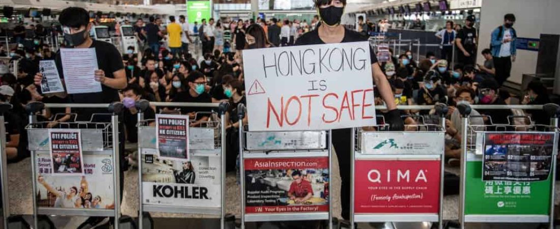 A Protester standing behind luggage trolleys while holding up a placard  in Hong Kong International Airport in Hong Kong on August 12, 2019 , Tens of Thousands Protester are seen gather in Hong Kong international airport in protest of Police Brutally and the extradition bill -- Protester Clash with Police yesterday in Hong Kong.  (Photo by Vernon Yuen/NurPhoto via Getty Images)