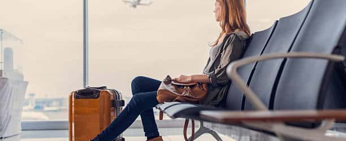 Start of her journey. Beautiful young woman looking out window at flying airplane while waiting boarding on aircraft in airport lounge