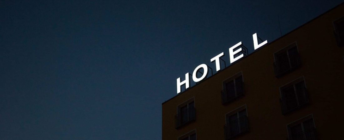 low-angle photo of Hotel lighted signage on top of brown building during nighttime