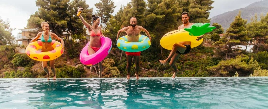 Friends with inflatable rings jumping in the swimming pool