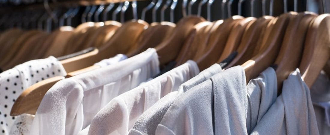 43436952 - white and gray tone clothes hanging on a rack in a designer clothes store, selective focus, horizontal