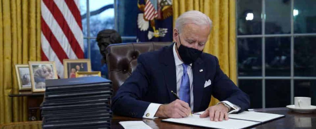 President Joe Biden signs his first executive order in the Oval Office of the White House on Wednesday, Jan. 20, 2021, in Washington. (AP Photo/Evan Vucci)