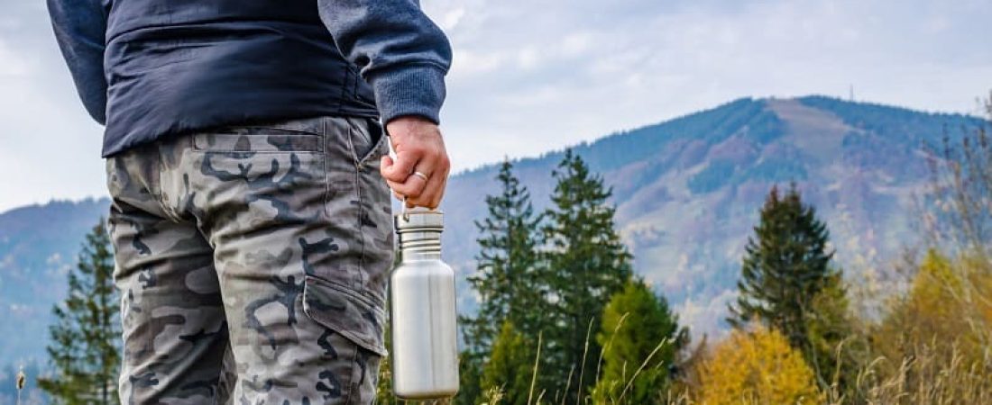 Man holding a bottle on the carpathian mountains background